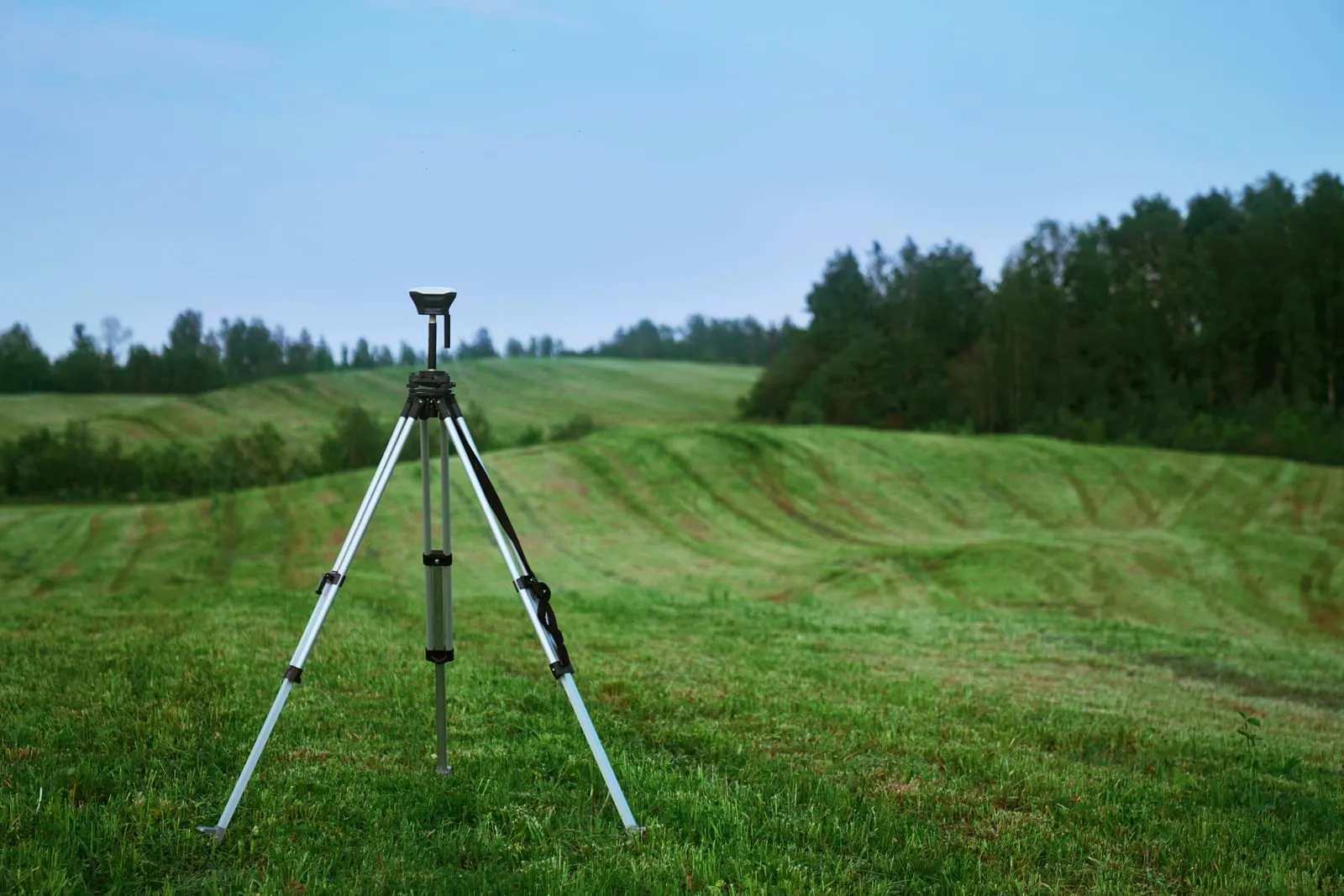 Survey instrument on a tripod in a green field